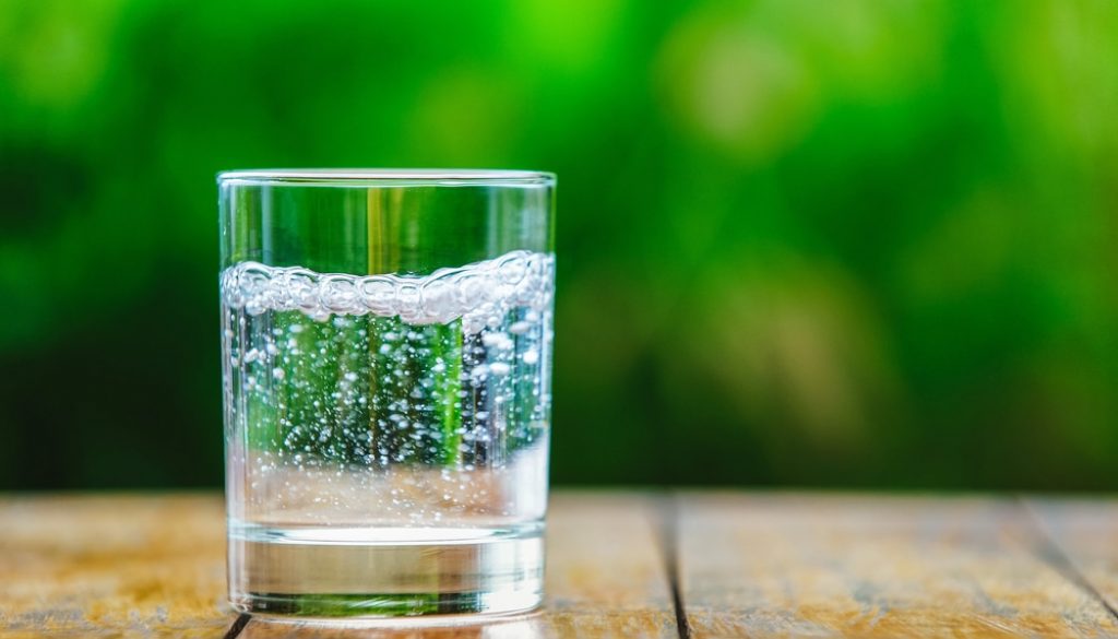 A,Glass,Of,Water,On,Green,Background.,The,Wooden,Table.