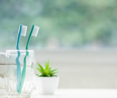 The,Toothbrushes,In,A,Glass,And,White,Towels,With,Copy